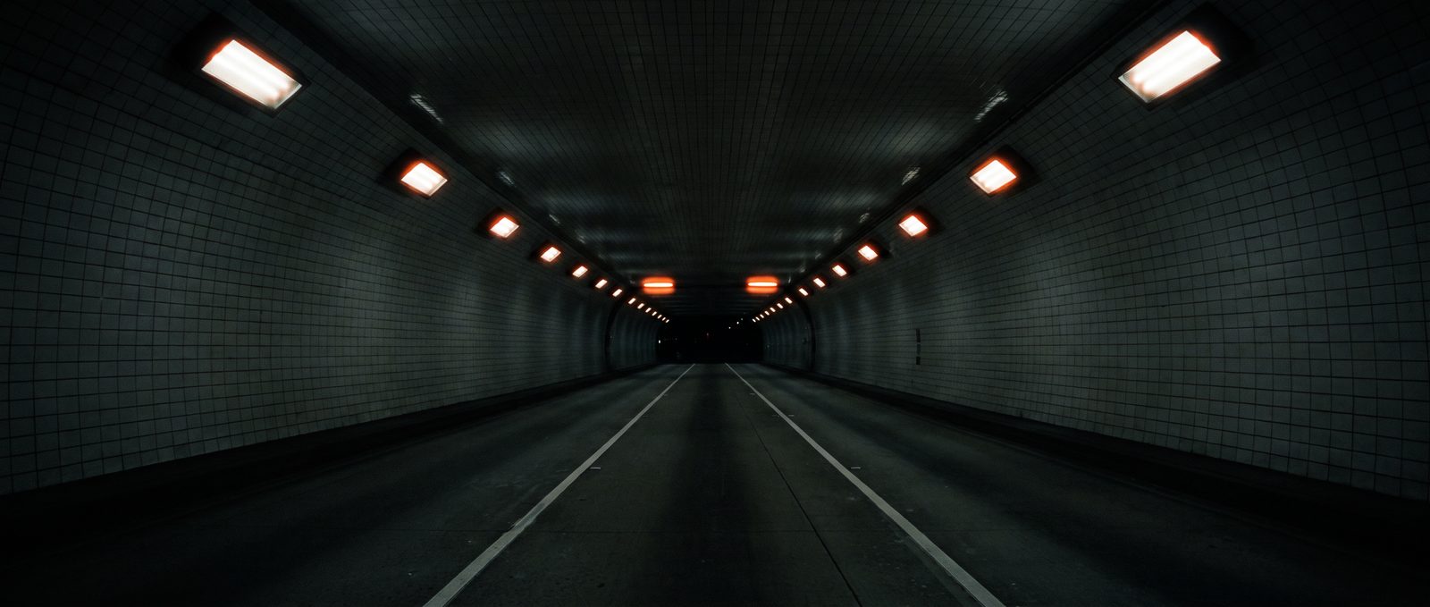 The tunnel: An empty tiled tunnel, sodium fixtures along the crown.